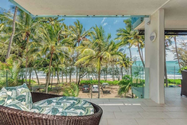 A balcony with a view of the beach and palm trees.
