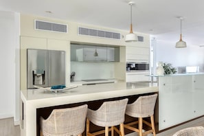 Una cucina moderna con isola centrale, sgabelli da bar e luci a sospensione.