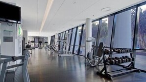 Un gimnasio moderno con diverso equipo de ejercicio, amplias ventanas y un diseño limpio y espacioso.