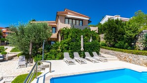 Un resort moderno con piscina, tumbonas y abundante vegetación.