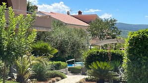 Un jardín ajardinado con un sendero pavimentado que conduce a un edificio con techo de tejas rojas.