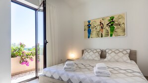 Un dormitorio con cama, un cuadro y vistas al exterior.