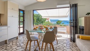 Una cocina moderna con comedor, ventanas amplias con vista al mar y un rincón de estar acogedor.