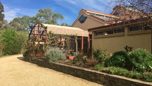 A house with a gravel driveway, a stone retaining wall, and a garden with various plants and flowers. - Ideal location to explore historic Strathalbyn, Wineries, good food and scenery (Strathalbyn)