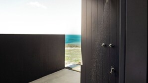 A dark wooden door with a view of the ocean through an open space. - Tranquility Bay of Fires - A beautiful beach house in a stunning location (The Gardens)