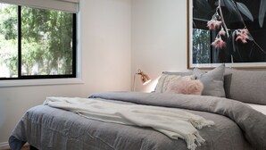 Een slaapkamer met een bed, een raam en een hangplant.