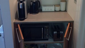 A kitchenette with a coffee maker, kettle, microwave, and tea box. - Private Suite, Spa, Double shower, log fire, rural views & farm animals (Emerald)