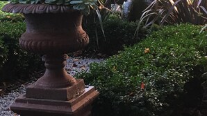 A garden with a large terracotta planter holding succulents, surrounded by various shrubs and trees. - Private Suite, Spa, Double shower, log fire, rural views & farm animals (Emerald)