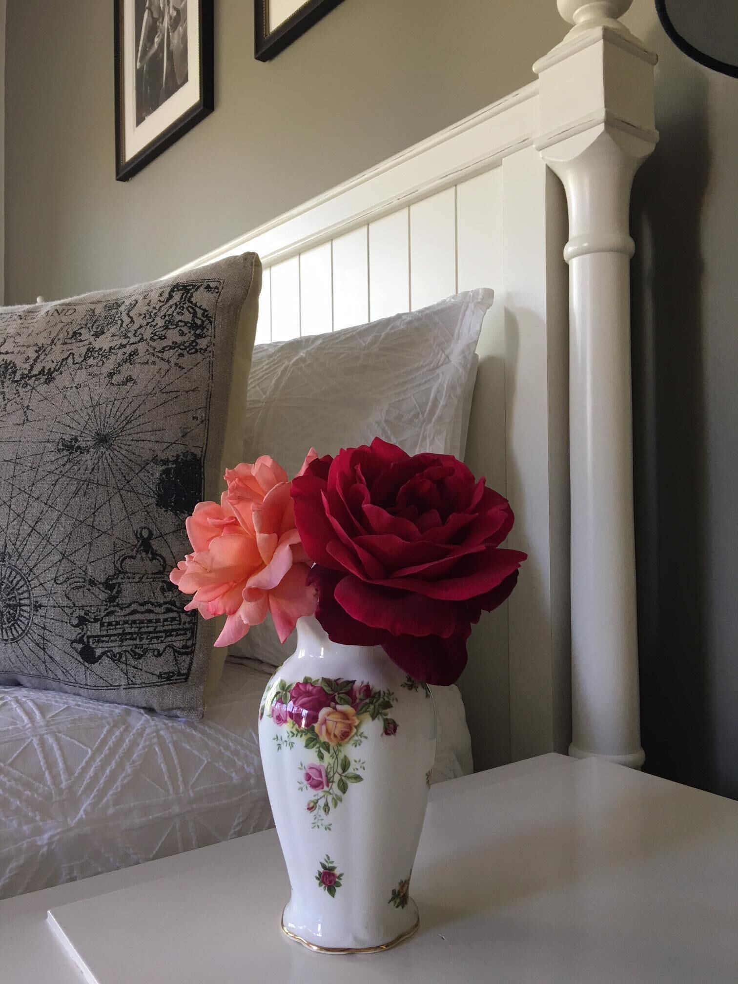 A white vase with floral patterns on a bedside table.