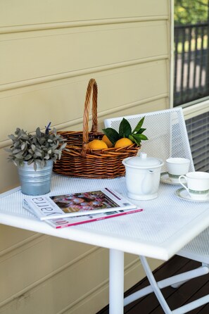 Taula amb una cistella de fruita, una planta en test, una tetera, tasses i una revista.