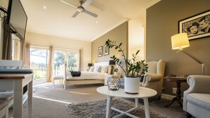 A spacious living room with a large bed, a dining table, and a sofa. - Private Suite, Spa, Double shower, log fire, rural views & farm animals (Emerald)