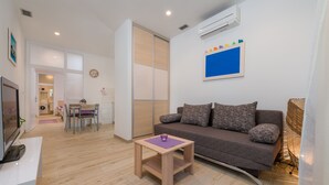 Un salon moderne avec un canapé, une petite table et un téléviseur.
