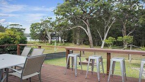 Un terrazzo con tavolo e sedie, una ringhiera e alberi sullo sfondo.