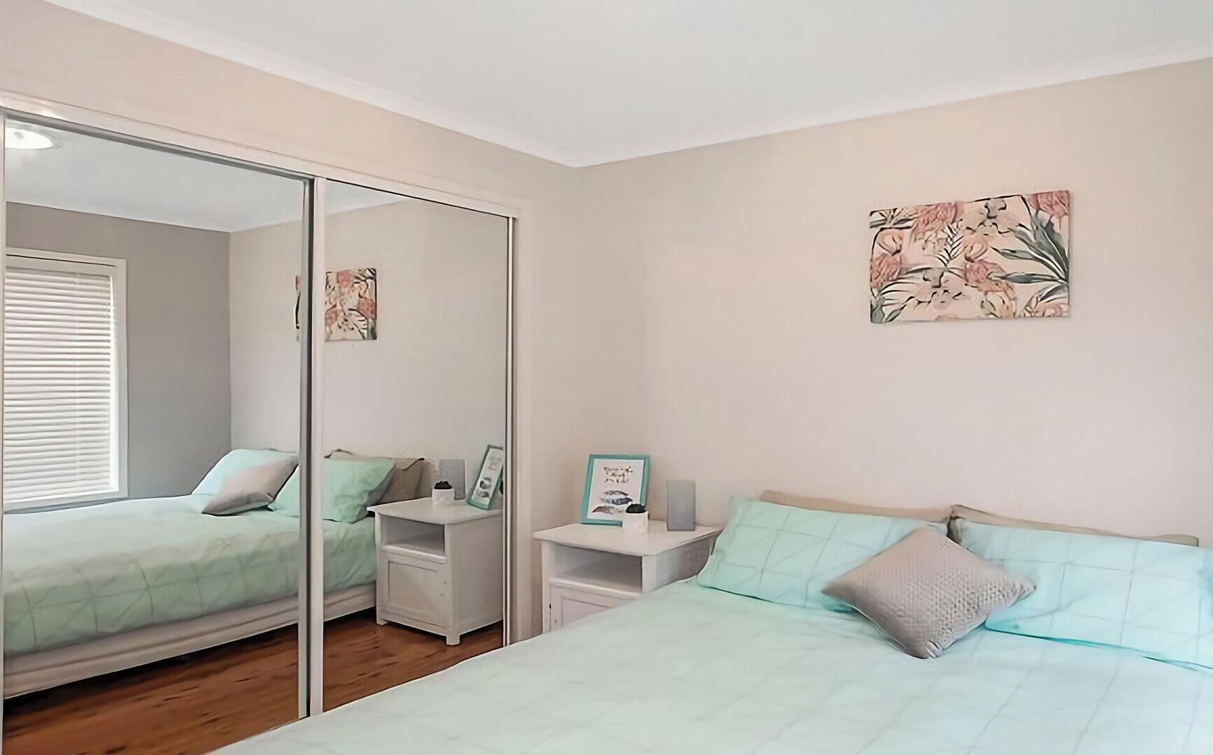 Une chambre à coucher avec un lit, des tables de chevet, un miroir et des œuvres d’art accrochées au mur.