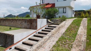 Une maison moderne à deux étages, avec un escalier en pierre menant à l’entrée.