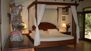 A four-poster bed with white linens, two bedside tables with lamps, and a statue on a dresser. - Villas Casa Loma - Suite 203 : Tropical Villa with Pool and Spectacular Views (Playa Flamingo)