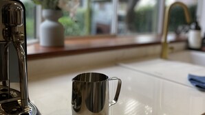 Un plan de travail de cuisine avec une machine à café et un mug en acier inoxydable.
