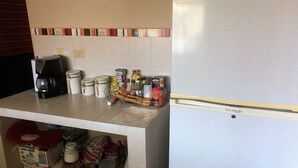 A kitchen with a refrigerator, coffee maker, and various containers.