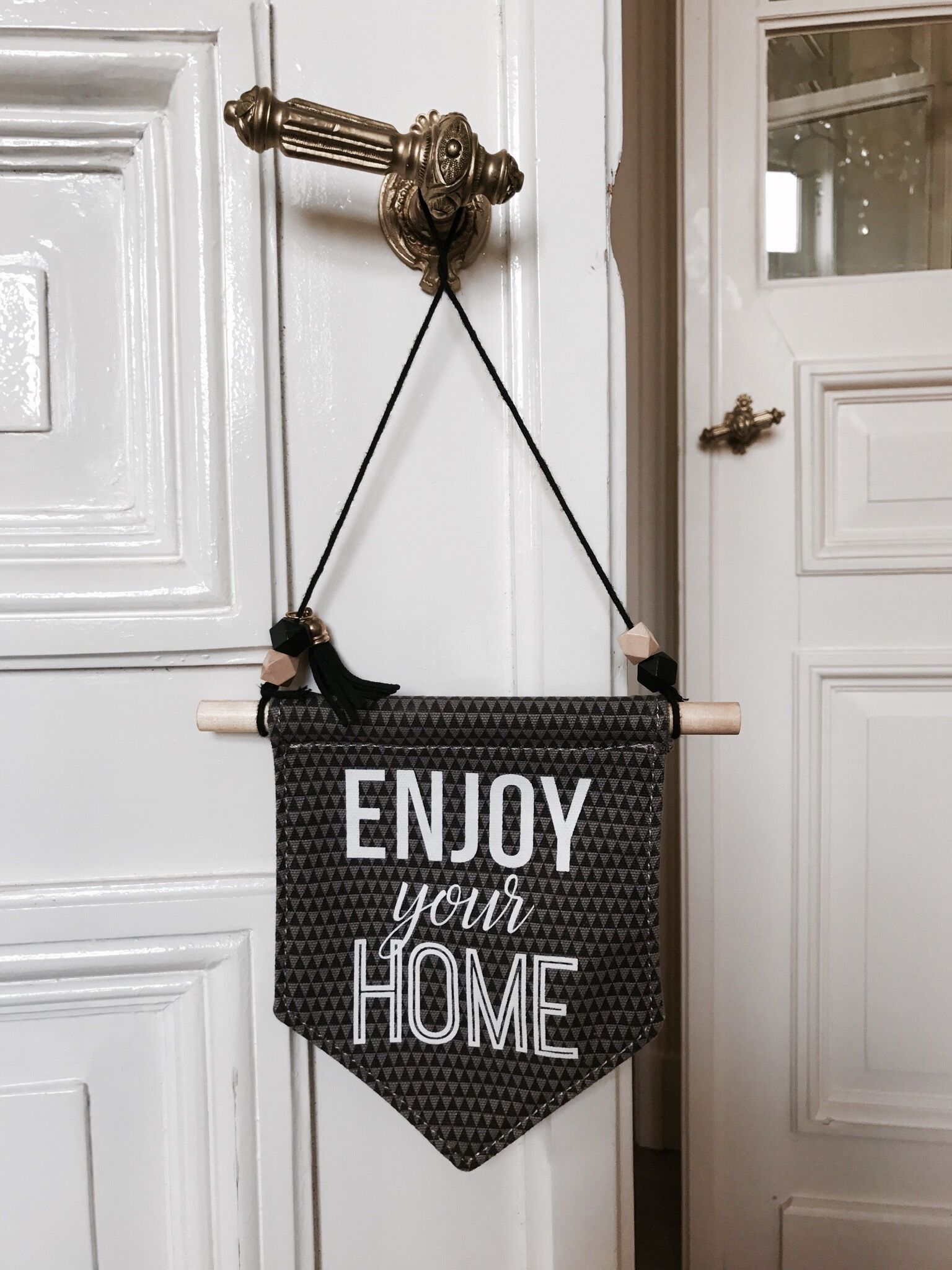 A decorative sign with the text "ENJOY your HOME" hanging on a door.