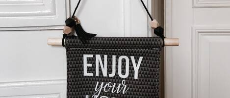A decorative sign with the text "ENJOY your HOME" hanging on a door.