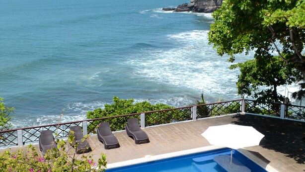 A pool with lounge chairs, a view of the ocean, and a grassy area. - AMAZING BEACH HOUSE ON A CLIFF, Spectacular OCEAN VIEWS & private beach access  (El Sunzal)