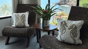 A room with a view of the ocean, featuring two wicker chairs with matching cushions, a small table with a plant, and a window with curtains. - AMAZING BEACH HOUSE ON A CLIFF, Spectacular OCEAN VIEWS & private beach access  (El Sunzal)