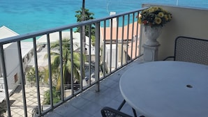 A balcony with a view of the sea, featuring a table and chairs, a railing, and a flower arrangement. - Vacation and Relaxation  (Montego Bay)