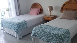 A hotel room with two beds, each with a patterned bedspread, a bedside table with a lamp, and a framed picture on the wall. - Vacation and Relaxation  (Montego Bay)