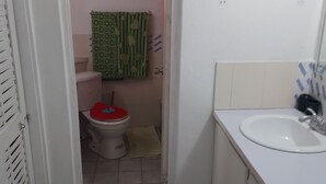 A narrow bathroom with a toilet, a sink, and a towel rack. - Vacation and Relaxation  (Montego Bay)