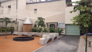 A courtyard with a play area, a covered seating area, and a building with a green garage door. - Jager 2 Tour As / 1-room APP with AC, Wi-Fi, in the pedestrian zone (Ljubljana)
