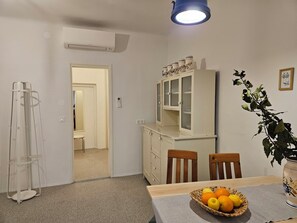 A dining area with a table set for two, a cabinet with glass doors, and a plant on the table. - Jager 2 Tour As / 1-room APP with AC, Wi-Fi, in the pedestrian zone (Ljubljana)