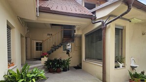 A residential building with a tiled roof, a staircase, potted plants, and a window with a metal grill. - Jager 2 Tour As / 1-room APP with AC, Wi-Fi, in the pedestrian zone (Ljubljana)