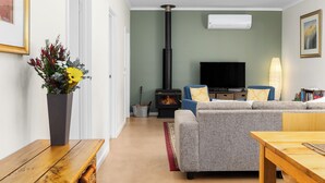 Ein Wohnzimmer mit einer Couch, einem Fernseher, einem Kamin und einem Holztisch.