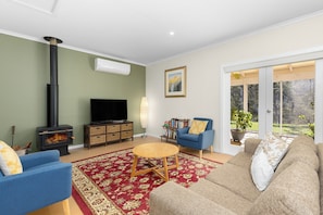 A living room with a fireplace, a television, a sofa, a coffee table, and a bookshelf.