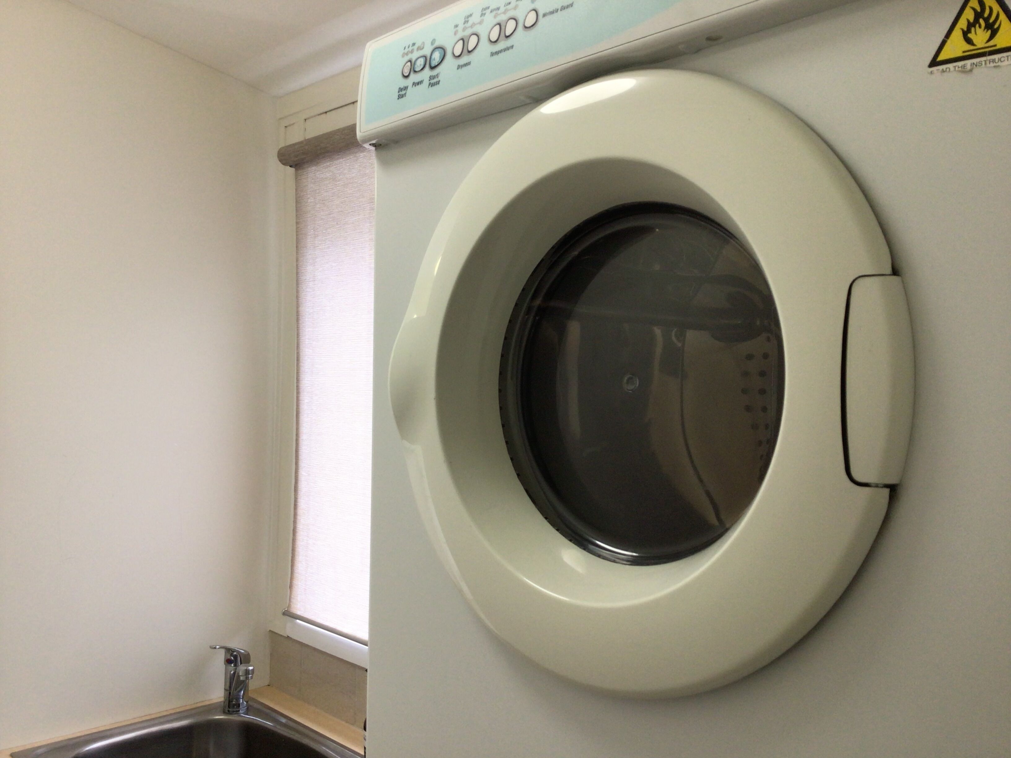 A front-loading washing machine with a control panel above it.