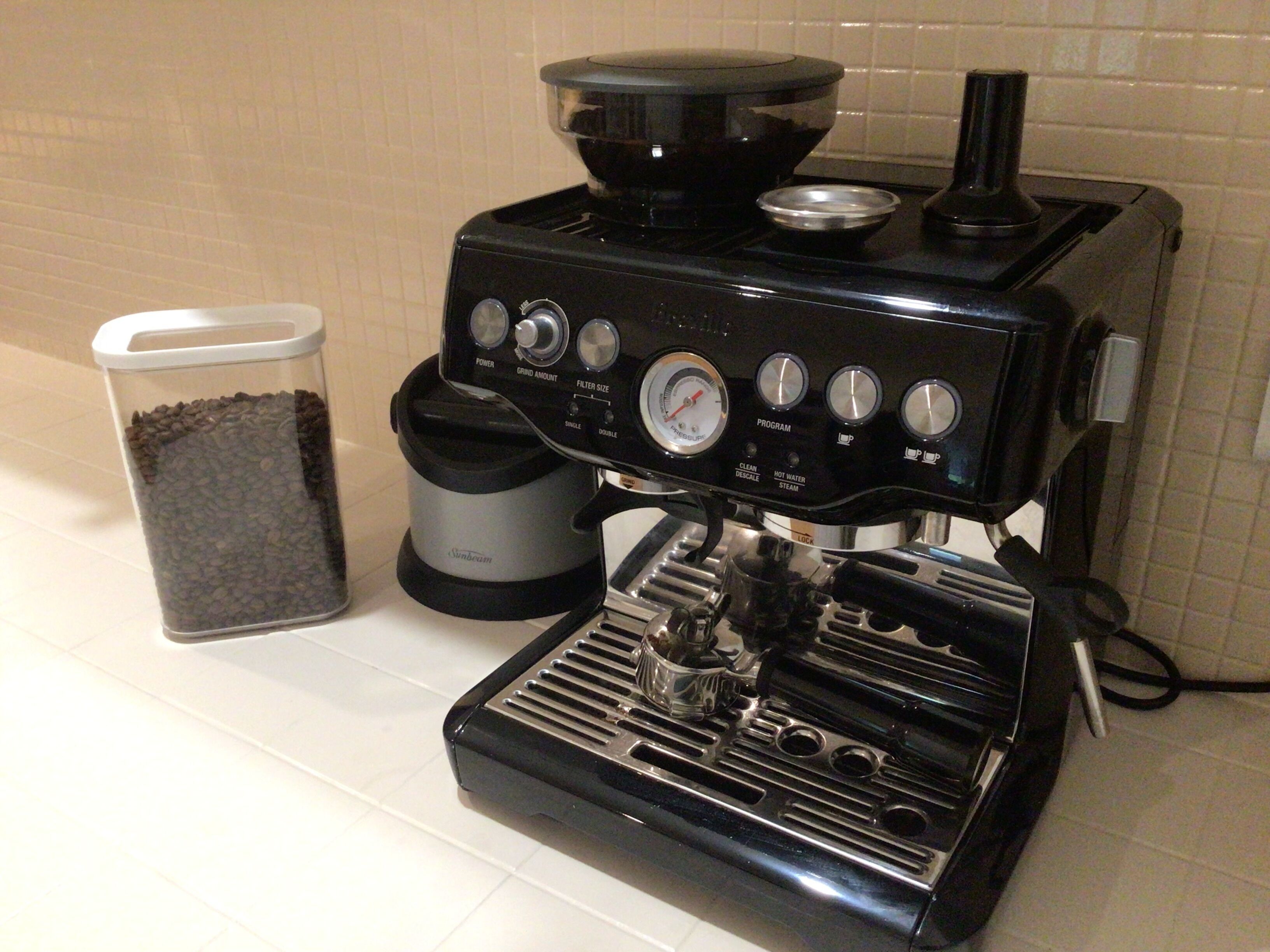 A coffee maker with a coffee pot, grinder, and water reservoir on a kitchen counter.