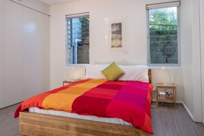 A bedroom with a bed, two bedside tables, a nightstand, a window, and a door. - Quiet Relaxation Retreat Near Bondi Beach, The Cute Place To Put Up Your Feet (North Bondi)