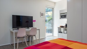 A bedroom with a bed, a desk with a chair, a television, a microwave, and a sliding glass door to a balcony. - Quiet Relaxation Retreat Near Bondi Beach, The Cute Place To Put Up Your Feet (North Bondi)