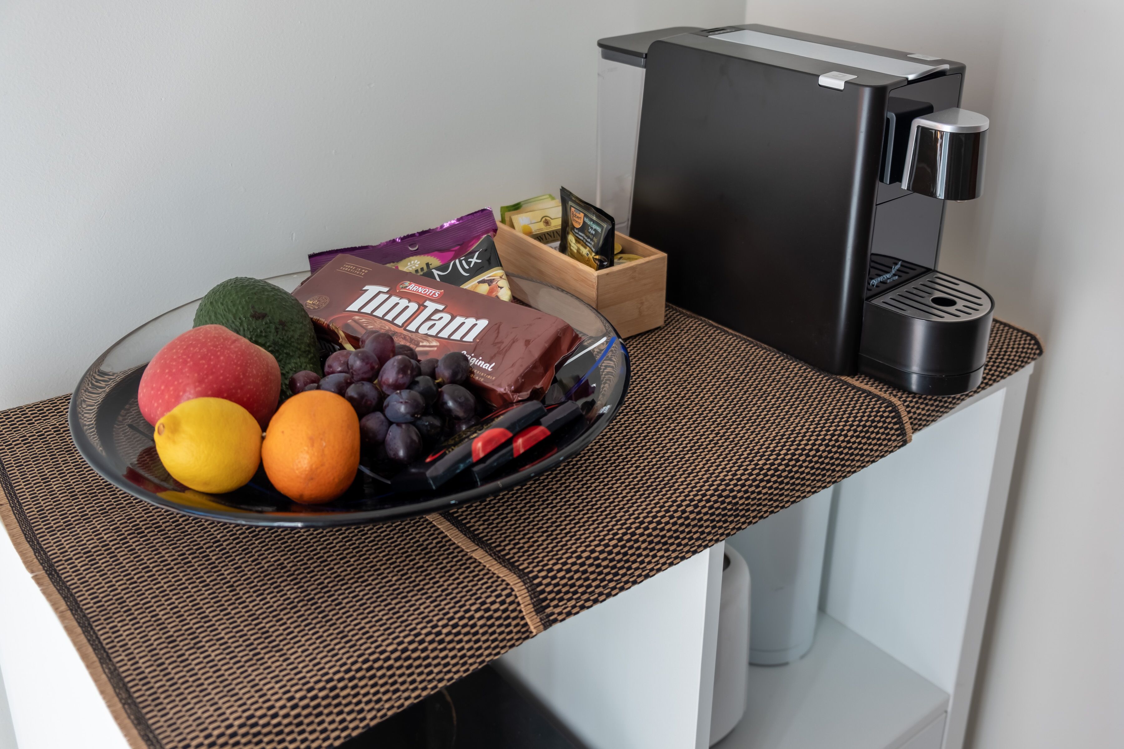 Ein Frühstücksbuffet mit Früchten, einer Schokoladentafel und einer Kaffeemaschine auf einem modernen Tisch.