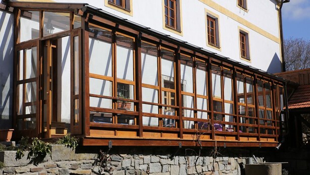 A traditional building with a stone foundation, wooden window frames, and a balcony with a wooden railing. - Waterwheel apartment at Kamenný potok (Kájov)