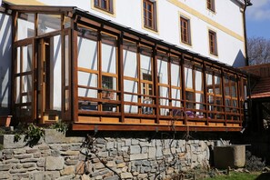 Il s’agit d’un bâtiment traditionnel, doté de fondations en pierre, de cadres de fenêtres en bois et d’un balcon agrémenté d’une balustrade en bois.