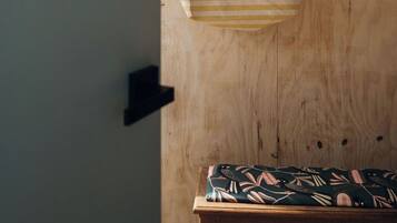 A wooden wall with a hanging striped bag and a light bulb.