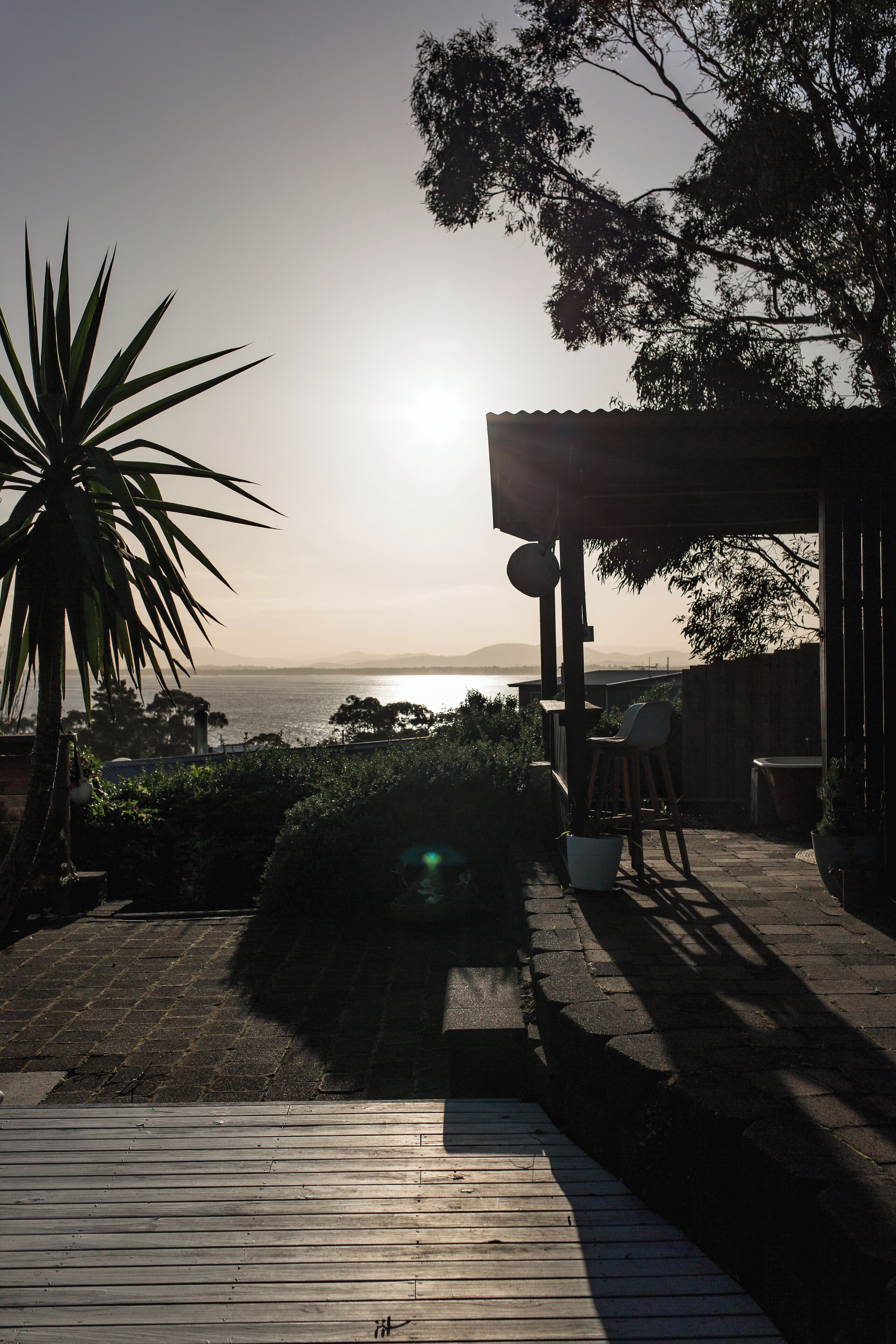 Un patio con vistas al mar, una pérgola de madera y un conjunto de muebles para sentarse.