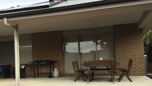 A covered patio with a brick exterior, a grill, and a table with chairs. - Marysville Views - Peaceful Snow Escape | Spacious 4BR Retreat (Marysville)