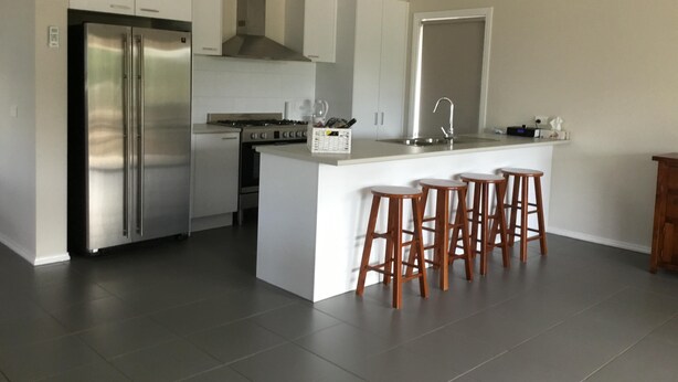 A modern kitchen with a stainless steel refrigerator, a gas stove, and a large island with bar stools. - Marysville Views - Peaceful Snow Escape | Spacious 4BR Retreat (Marysville)