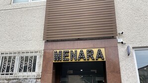 The exterior of a hotel named Menara with a modern design, featuring a prominent entrance and security cameras. - Hotel Menara (Mexico City)