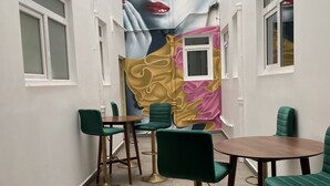 A narrow hallway with green chairs and a wooden table, white walls, and a large mural on one wall. - Hotel Menara (Mexico City)