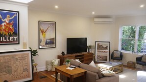 A modern living room with a large flat-screen TV, a sofa, a coffee table, and a map on the wall. - Amazing location - Walk to MCG/Swan St/Bridge Rd/Melbourne CBD (Richmond)