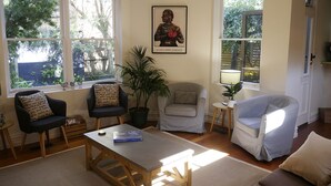 A living room with a wooden coffee table, two armchairs, a sofa, a potted plant, and a framed poster on the wall. - Amazing location - Walk to MCG/Swan St/Bridge Rd/Melbourne CBD (Richmond)