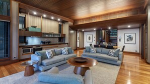 Ein geräumiges Wohnzimmer mit modernem Design, ausgestattet mit einer großen Eckcouch, einem Couchtisch und einer Küchenzeile mit Einbaugeräten.